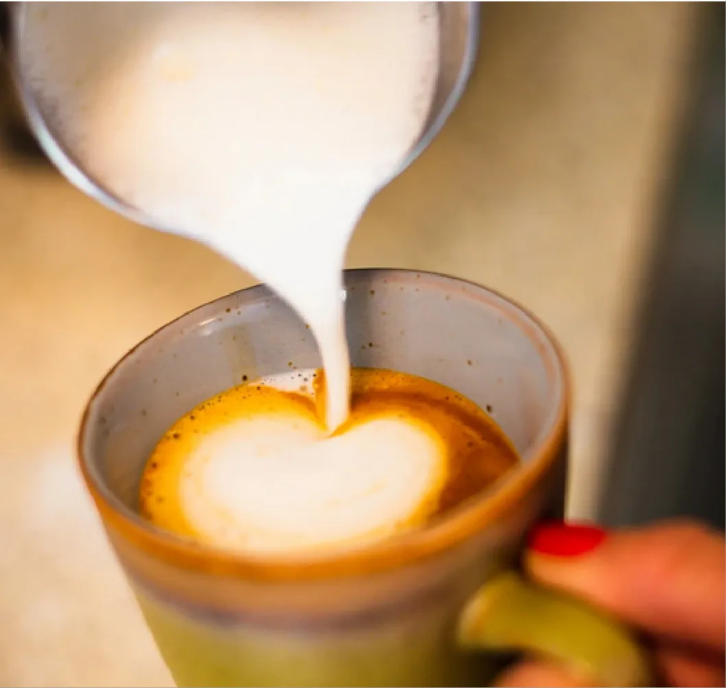 Schätze Bergen, Concept Store, Eine Frau gibt Milch in die Kaffeetasse